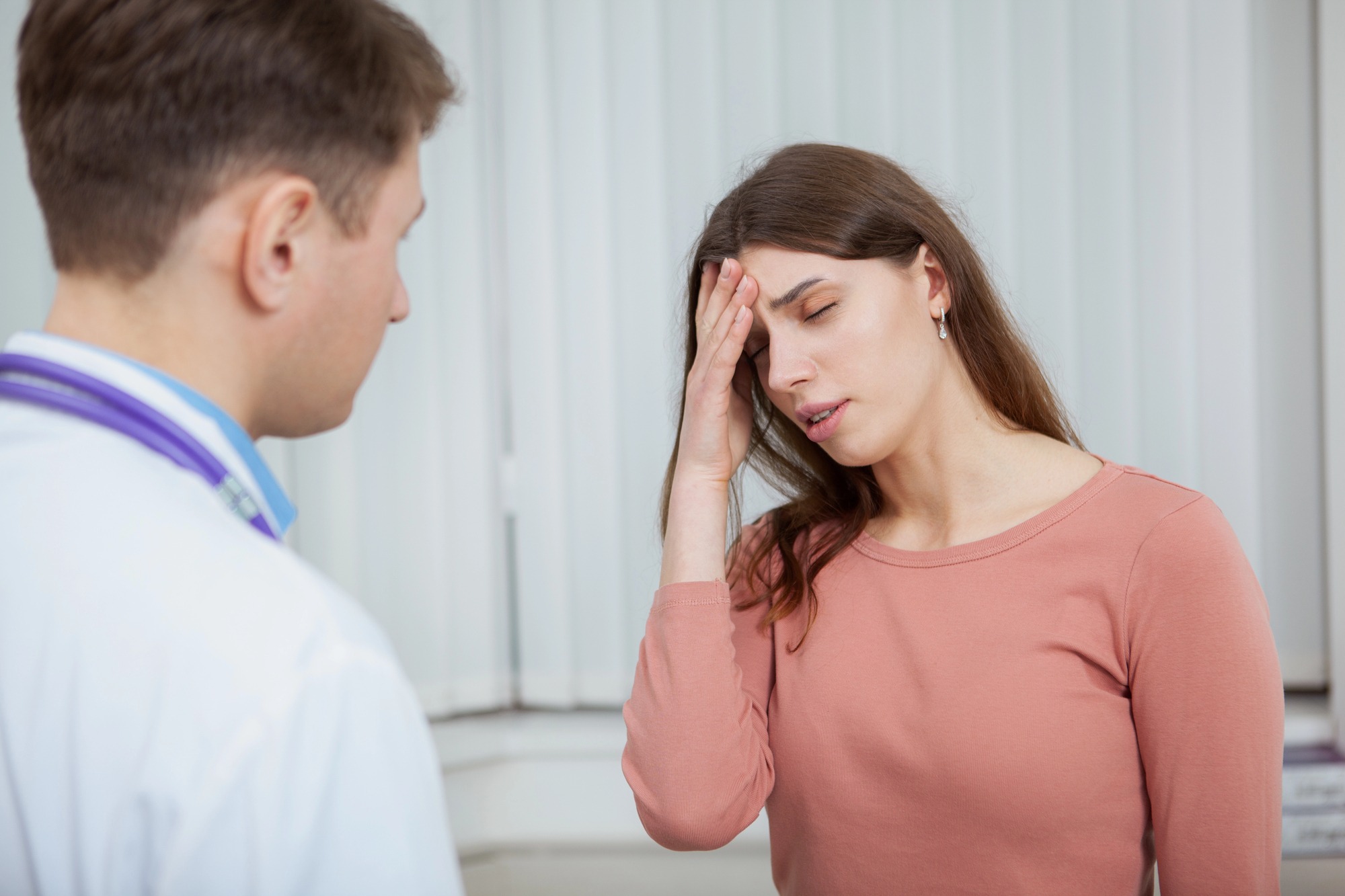 Doctor evaluating a patient with temporal migraine symptoms Patient experiencing temporal migraine pain during a medical consultation